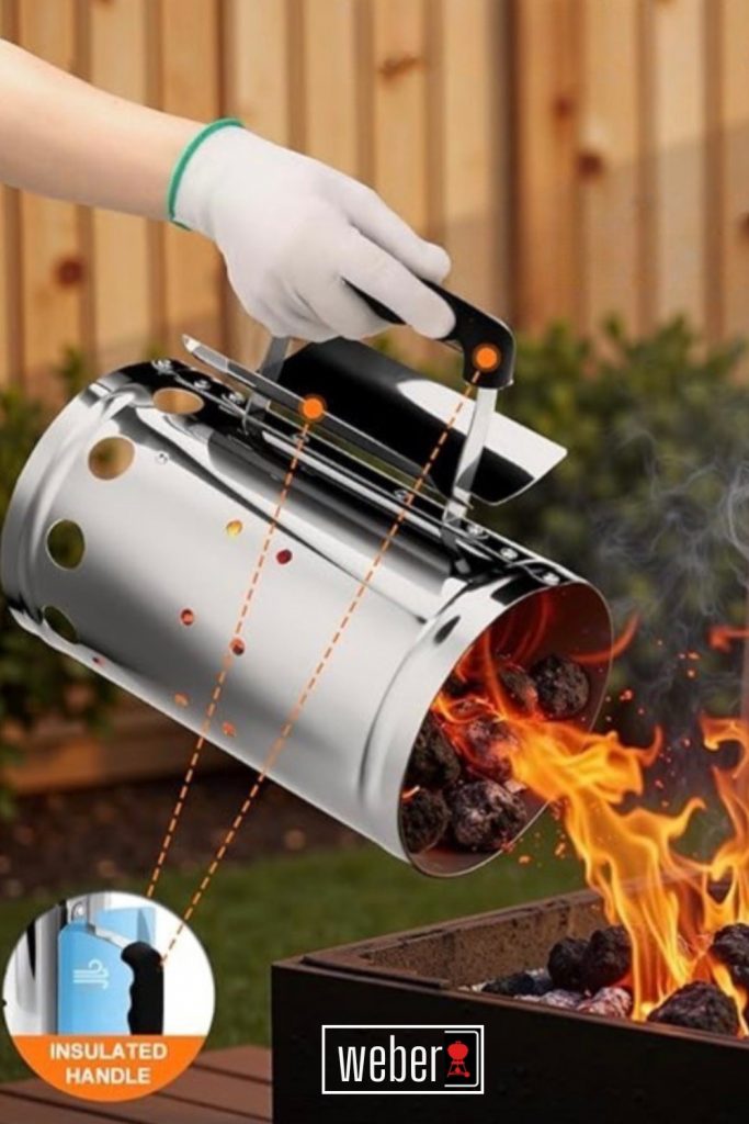 A person wearing a protective glove pouring hot, glowing charcoal from a Weber stainless steel chimney starter into a barbecue grill with orange flames visible.