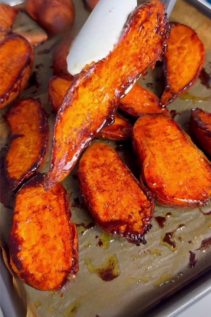 Perfectly roasted and caramelized sweet potato wedges on a baking sheet, showing a golden brown texture.