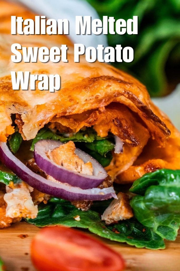 Close-up of a sliced Italian melted sweet potato wrap with fresh spinach and red onions.
