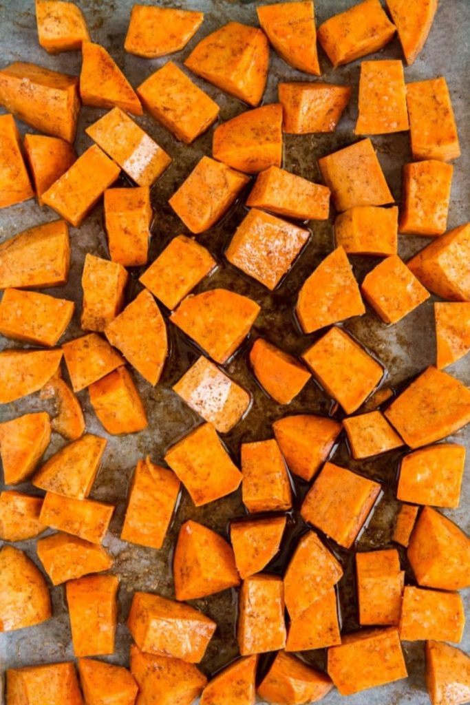Freshly diced sweet potato cubes spread evenly on a baking sheet for roasting.